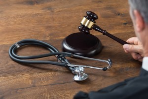 Cropped image of judge hitting gavel with stethoscope in courtroom